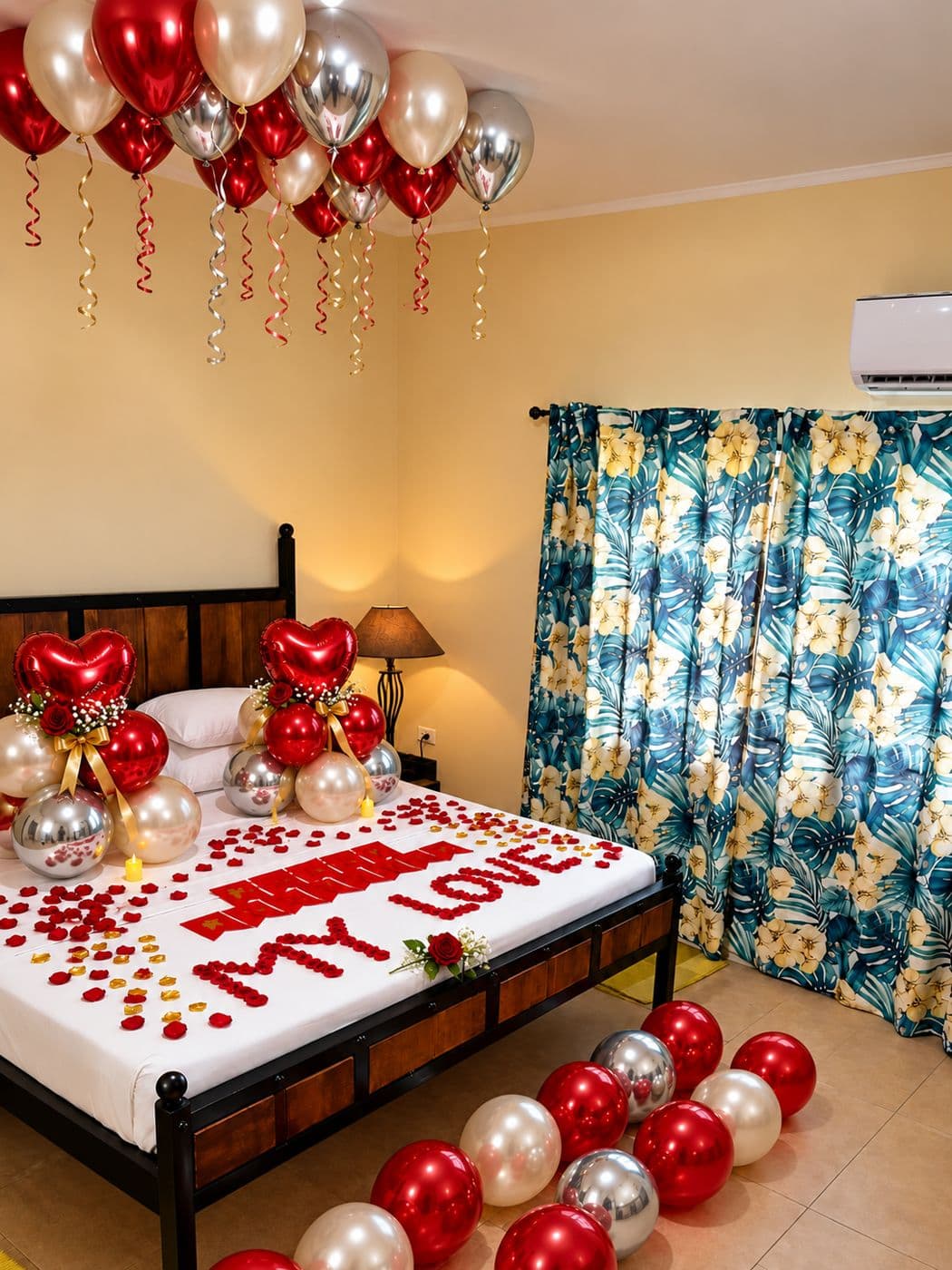 Bed with a message spelled in rose petals, surrounded by red and silver balloons